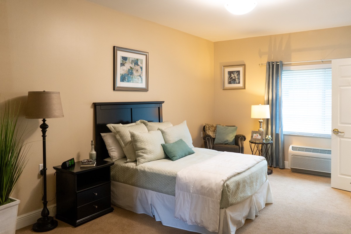 A cozy bedroom with a neatly made bed, decorative pillows, and elegant furniture.