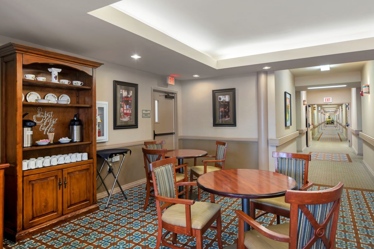 A cozy indoor dining area with wooden tables and chairs, decorative artwork, and warm lighting.