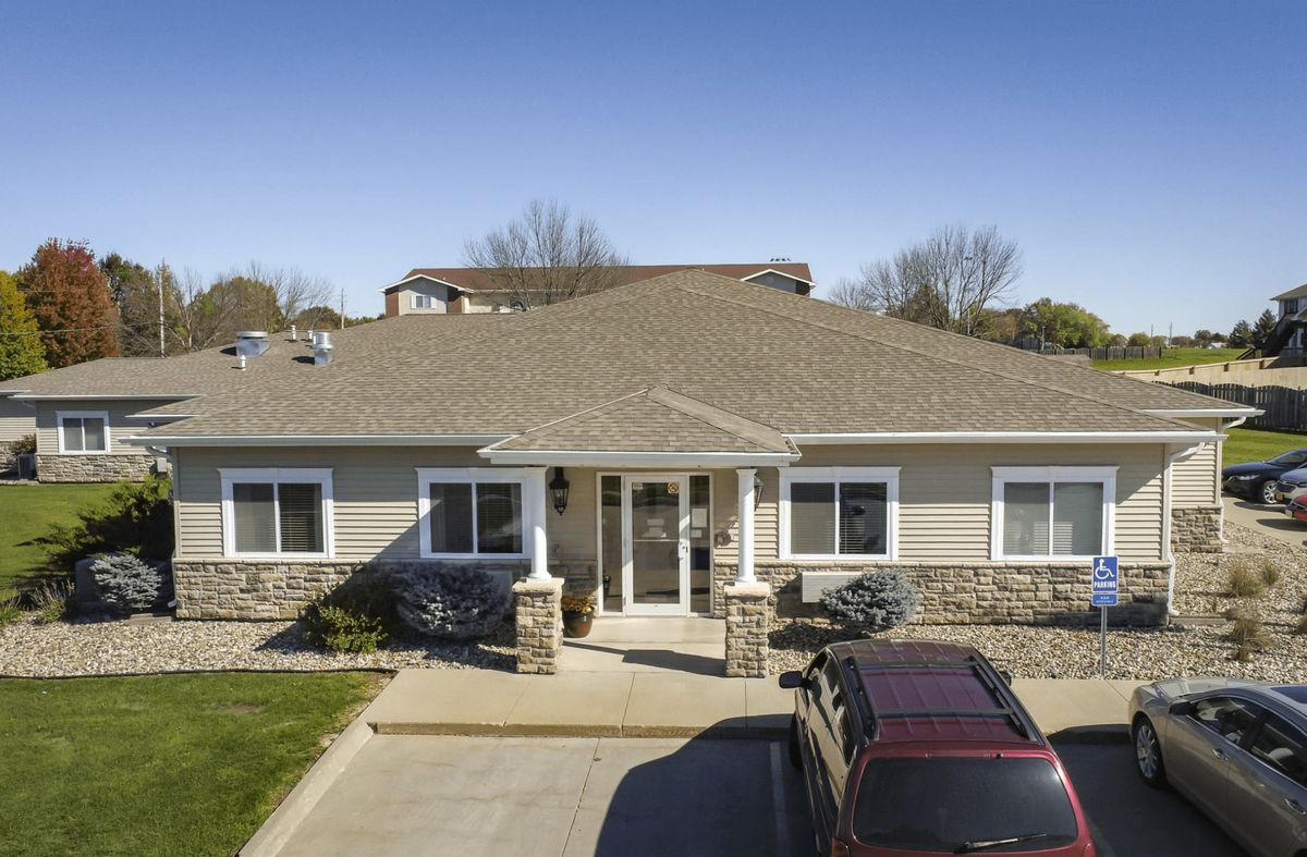 A suburban house with a driveway and parked cars on a sunny day.