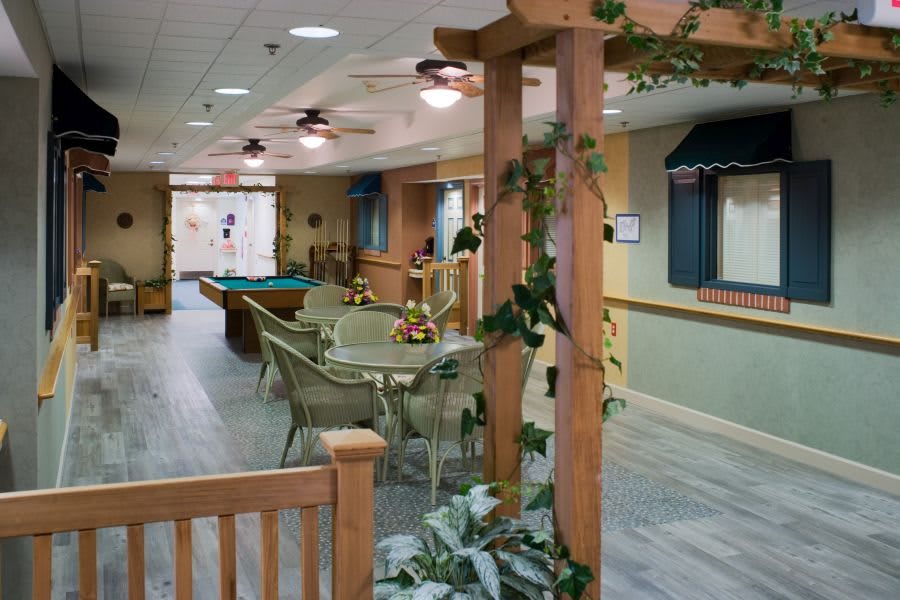A cozy recreation room featuring a pool table, seating area, and wooden accents with plants.