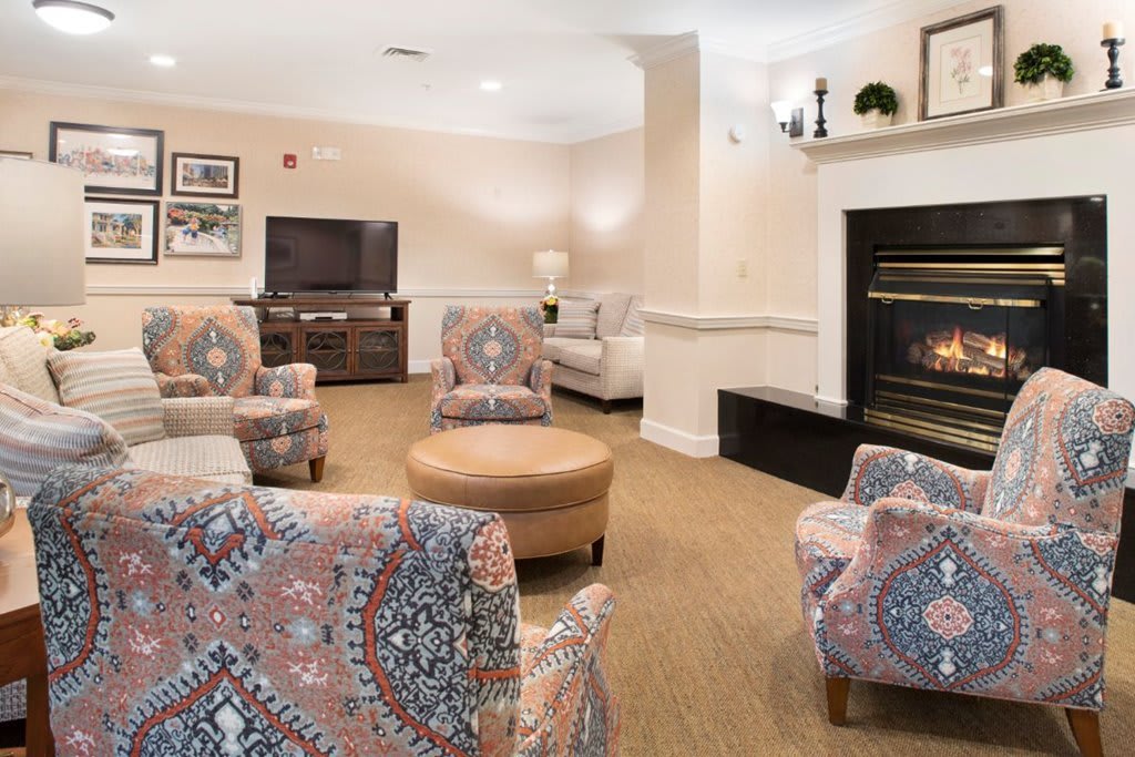 A cozy living room with patterned armchairs, a fireplace, and a television.