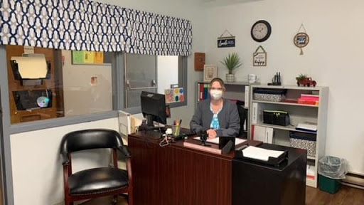 An individual wearing a mask sitting at their desk in an office setting.