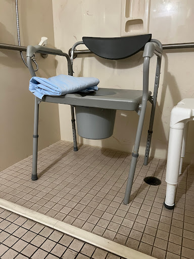 A commode chair designed for accessibility in a bathroom setting.