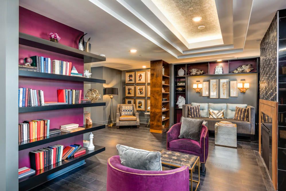 A modern living room with rich purple accents and stylish bookshelves, featuring plush seating and elegant lighting.