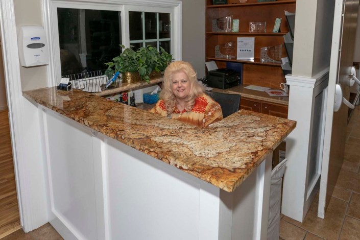 A woman sitting at a reception desk in an office setting.