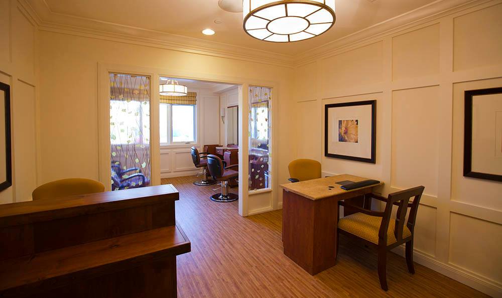 A well-lit office space featuring a desk, chairs, and large windows.