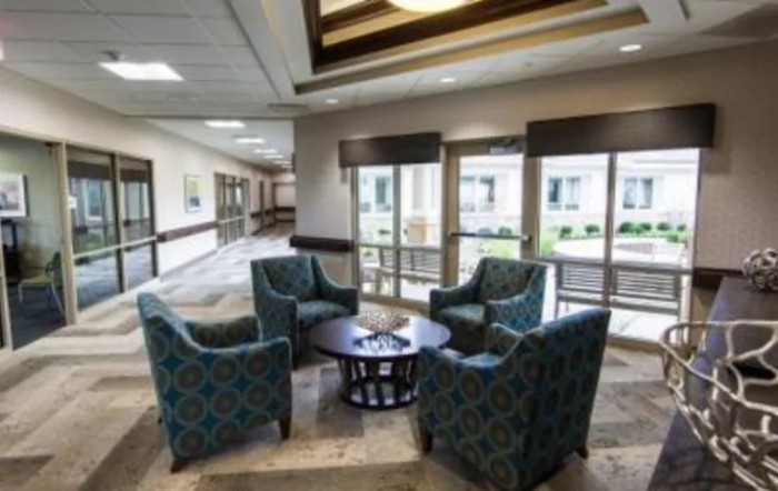 A cozy seating area in a modern lobby with four chairs around a small table, surrounded by large windows.