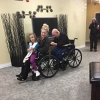 A family sitting together on a wheelchair indoors, sharing a moment of togetherness.