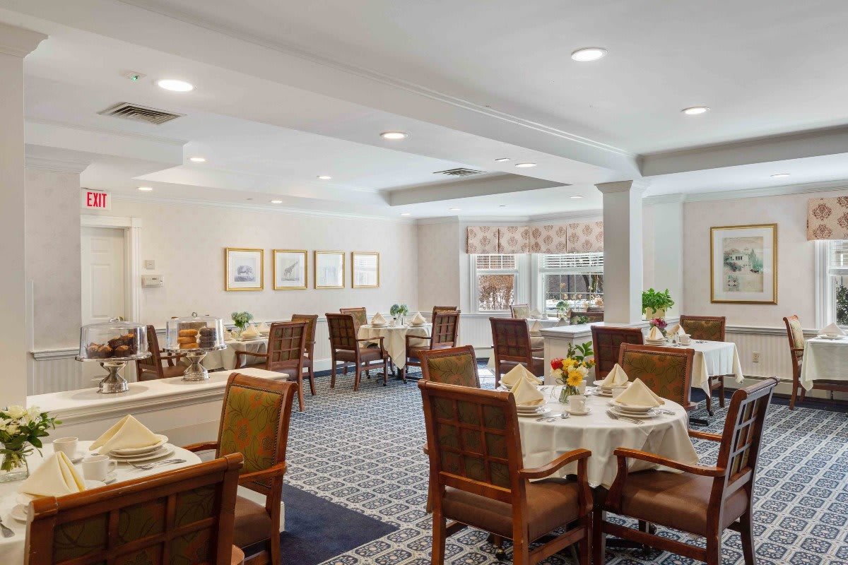 A well-lit dining area with elegantly set tables and comfortable chairs.
