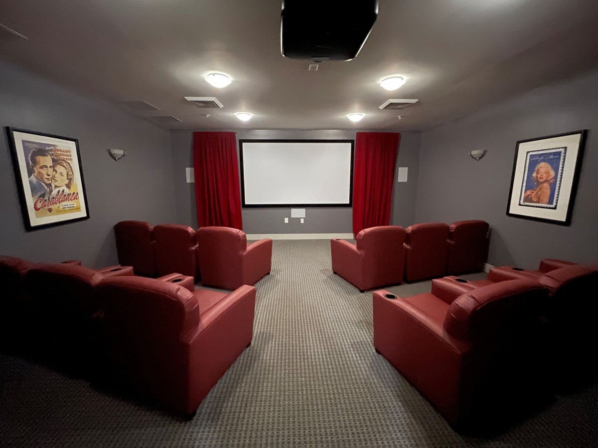 A cozy home theater with red armchairs and a large projector screen.