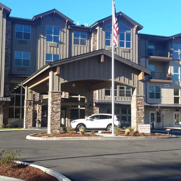 A modern building with a prominent entrance, featuring a flag and parked car.