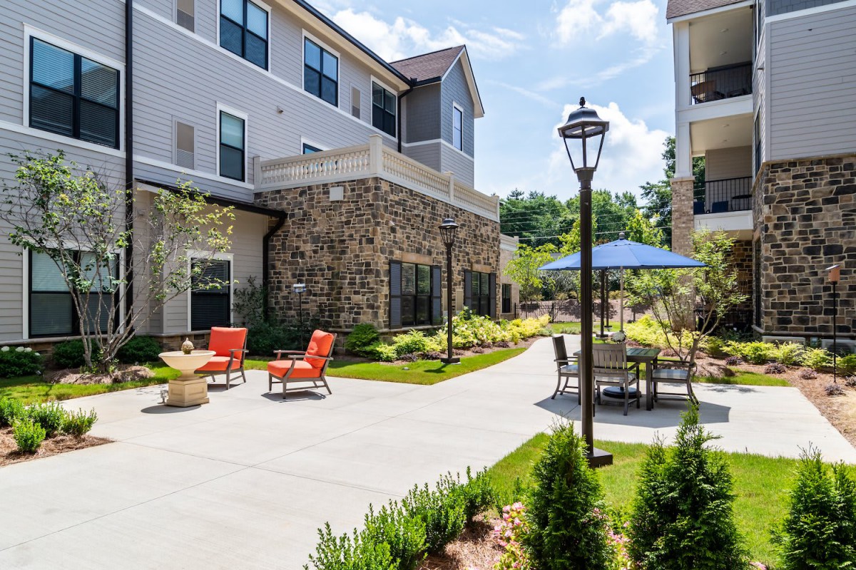 A modern apartment building with a landscaped courtyard and outdoor seating area.