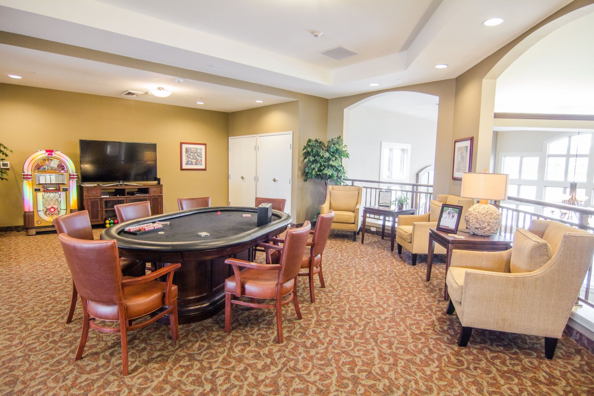 A cozy entertainment room with a poker table, comfortable seating, and a television.