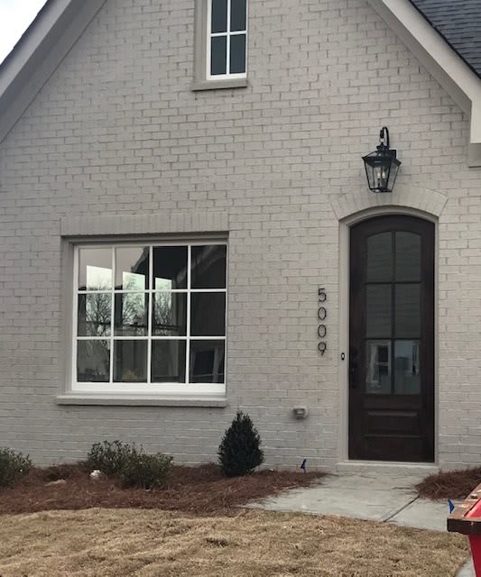 A charming house with a brick exterior and a lantern light by the front door.