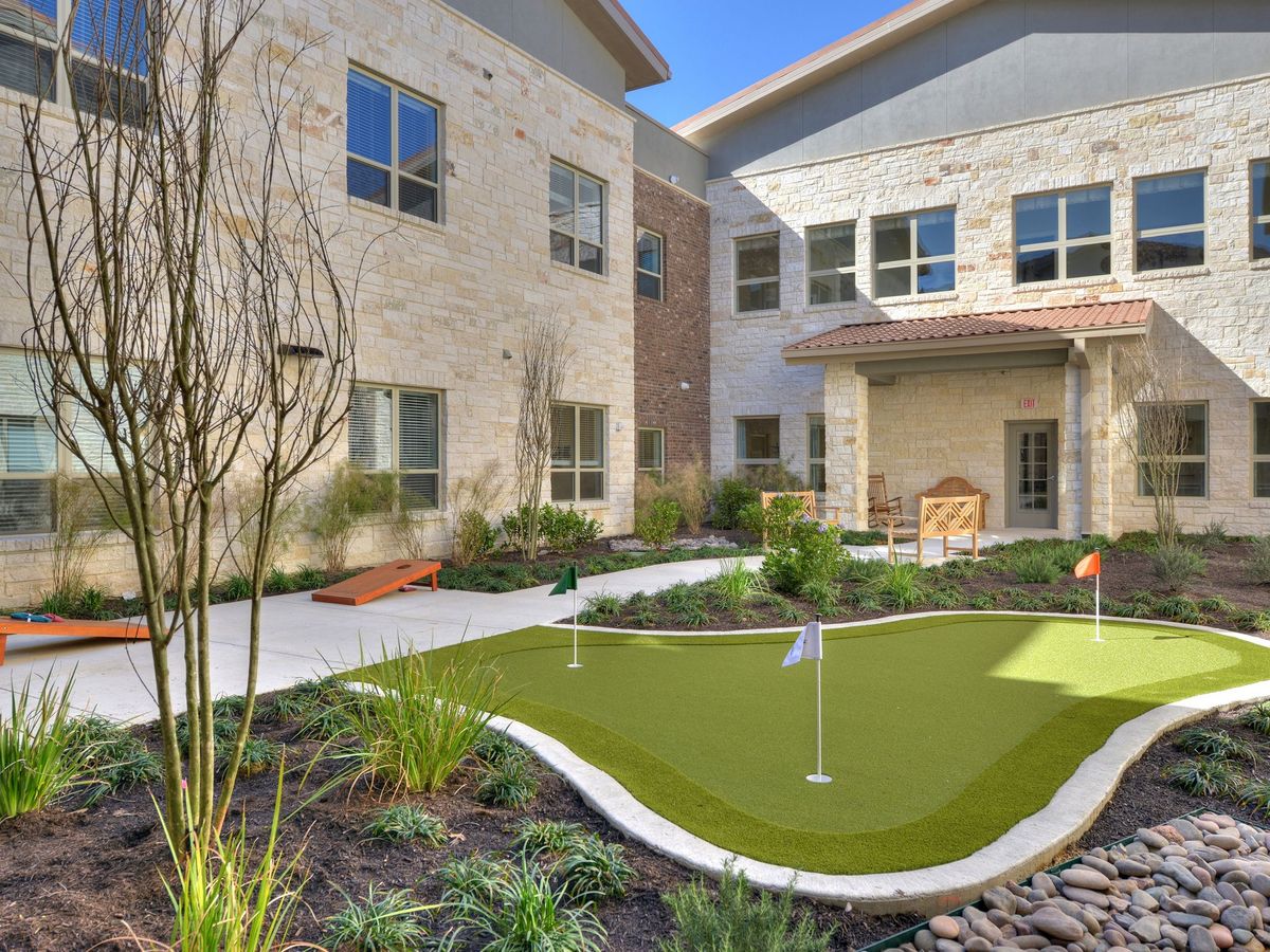 A courtyard with a mini golf course surrounded by modern architecture and greenery.