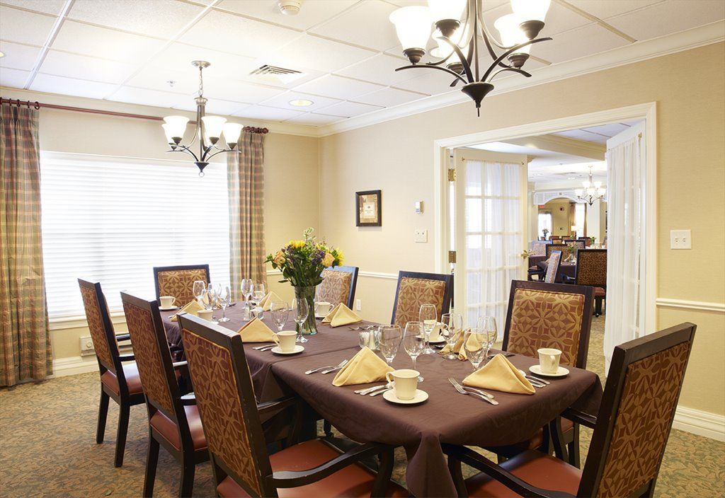 An elegantly set dining room with a large table, cushioned chairs, and ambient lighting.
