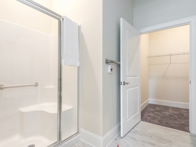 A modern bathroom with a glass shower and adjacent walk-in closet.