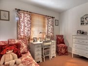 A cozy bedroom with a white desk and floral-patterned furnishings.
