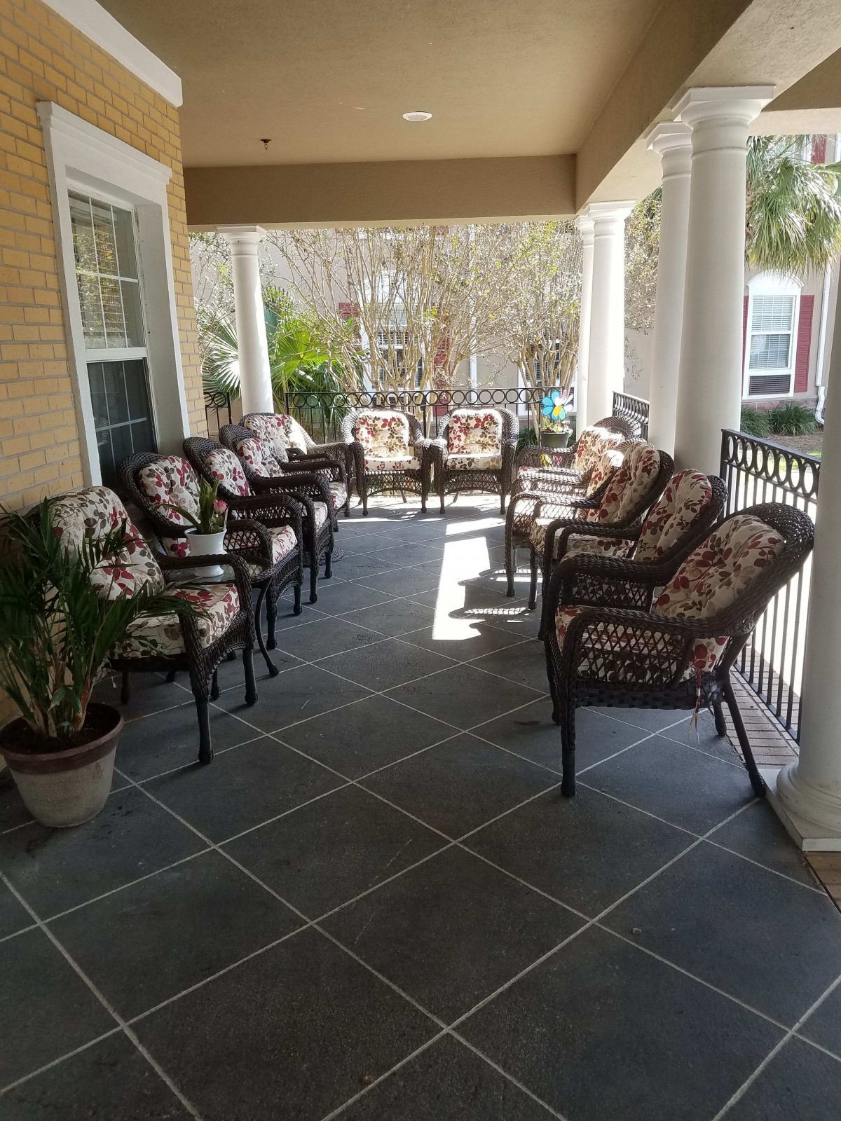 A welcoming porch with cushioned chairs and potted plants.