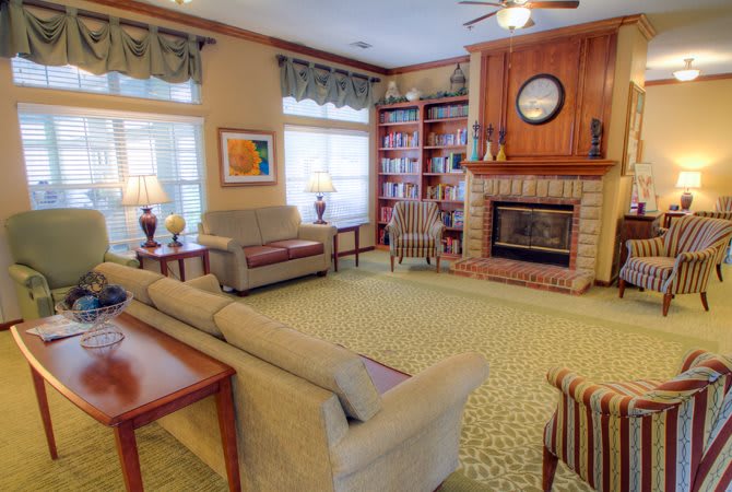 A cozy living room featuring a fireplace, comfortable sofas, armchairs, and bookshelves.