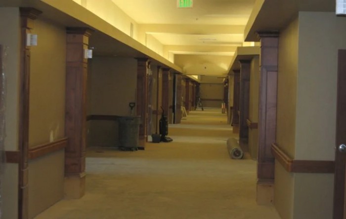 A long, indoor hallway with wooden columns and warm lighting.