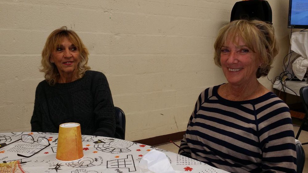 Two people sitting at a table, smiling indoors.