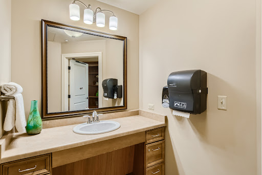 A well-lit bathroom featuring a stylish vanity, mirror, and hand dryer.