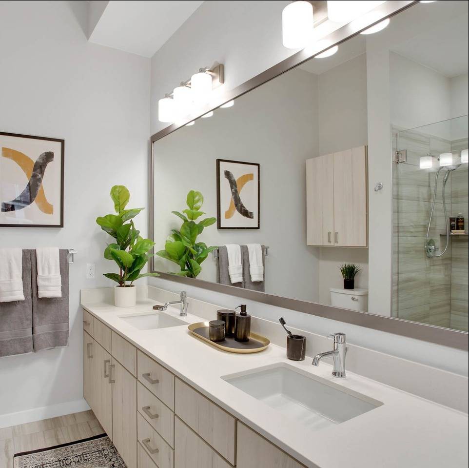 A modern bathroom with a large mirror, sleek counter, and stylish decor.
