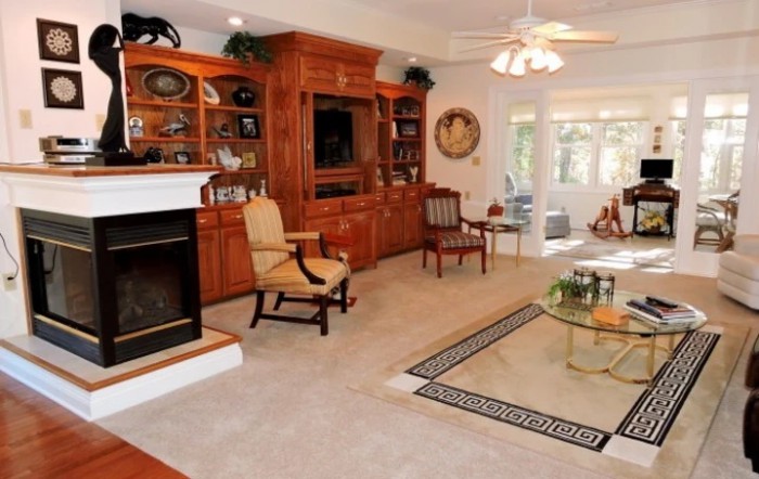 A cozy living room featuring a fireplace, wooden bookshelves, and comfortable seating.