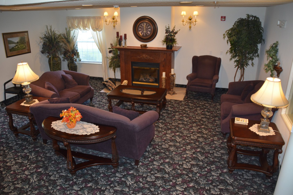 A cozy living room with a fireplace, couches, and armchairs arranged on a patterned carpet.