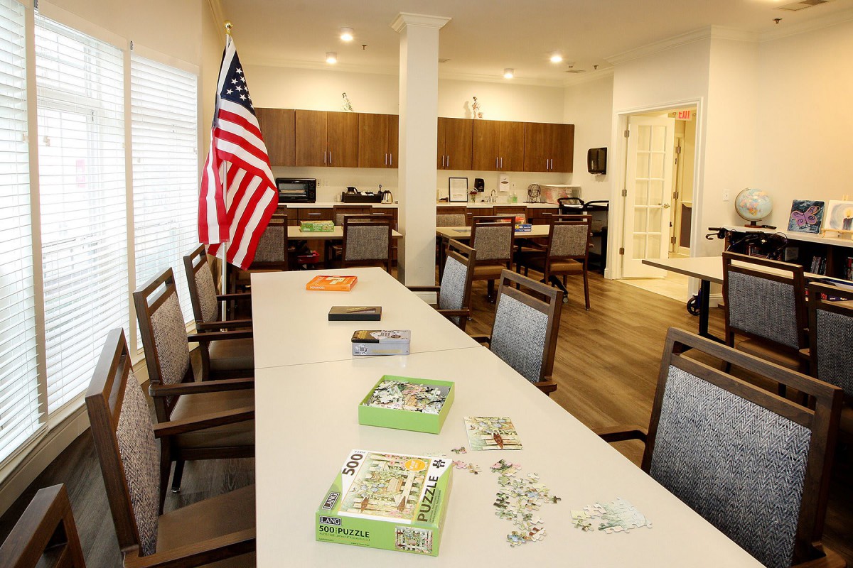 A meeting room setup with a long table, chairs, an American flag, and puzzles on the table.