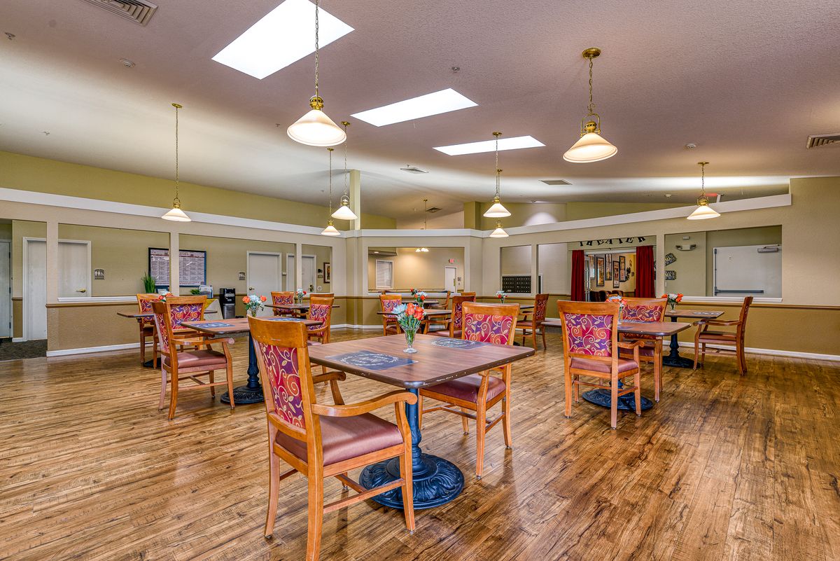 Spacious and well-lit dining area with wooden floors and multiple tables.