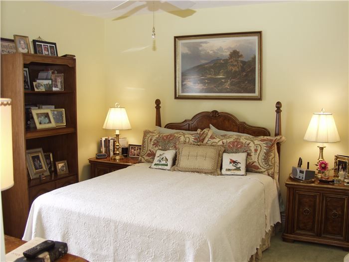 A cozy bedroom with a large bed, wooden furniture, and warm lighting.