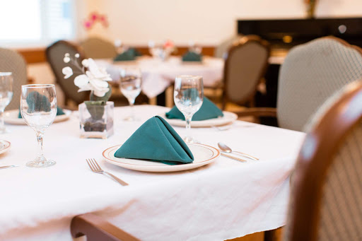 A beautifully arranged dining table with teal napkins, elegant glassware, and cutlery.