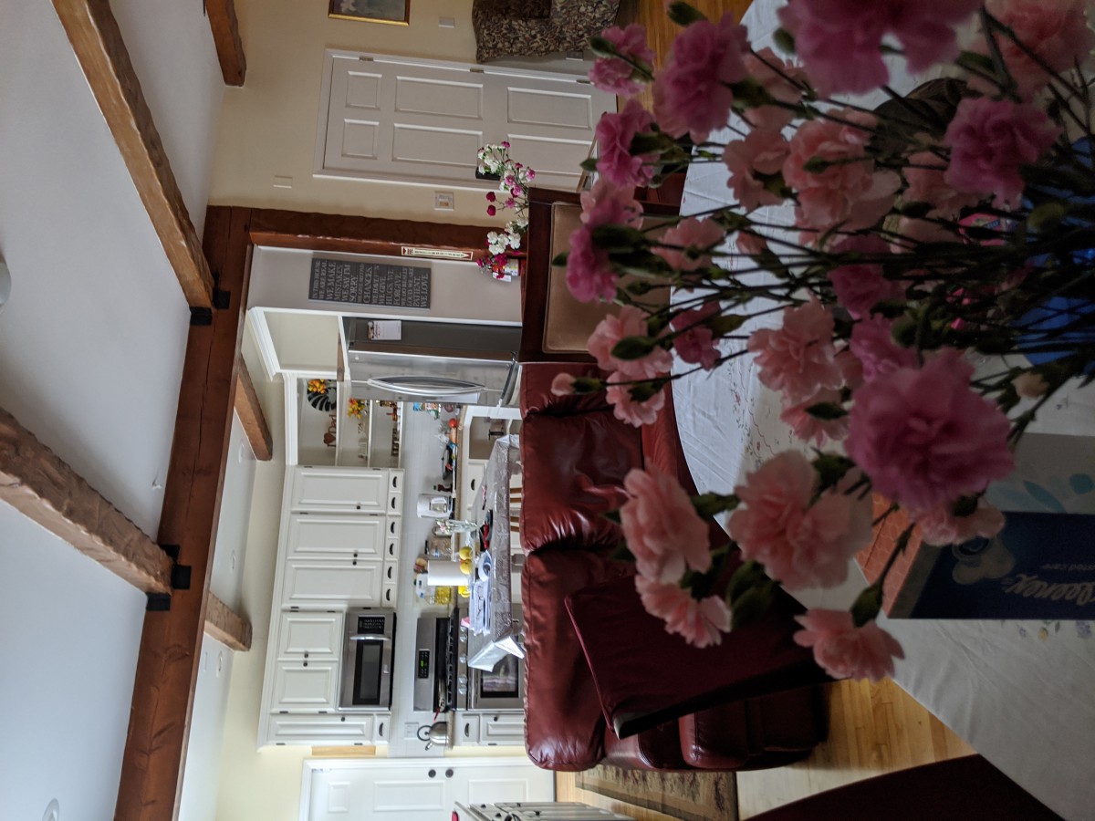 A cozy home interior featuring a kitchen and living room with pink flowers on the table.