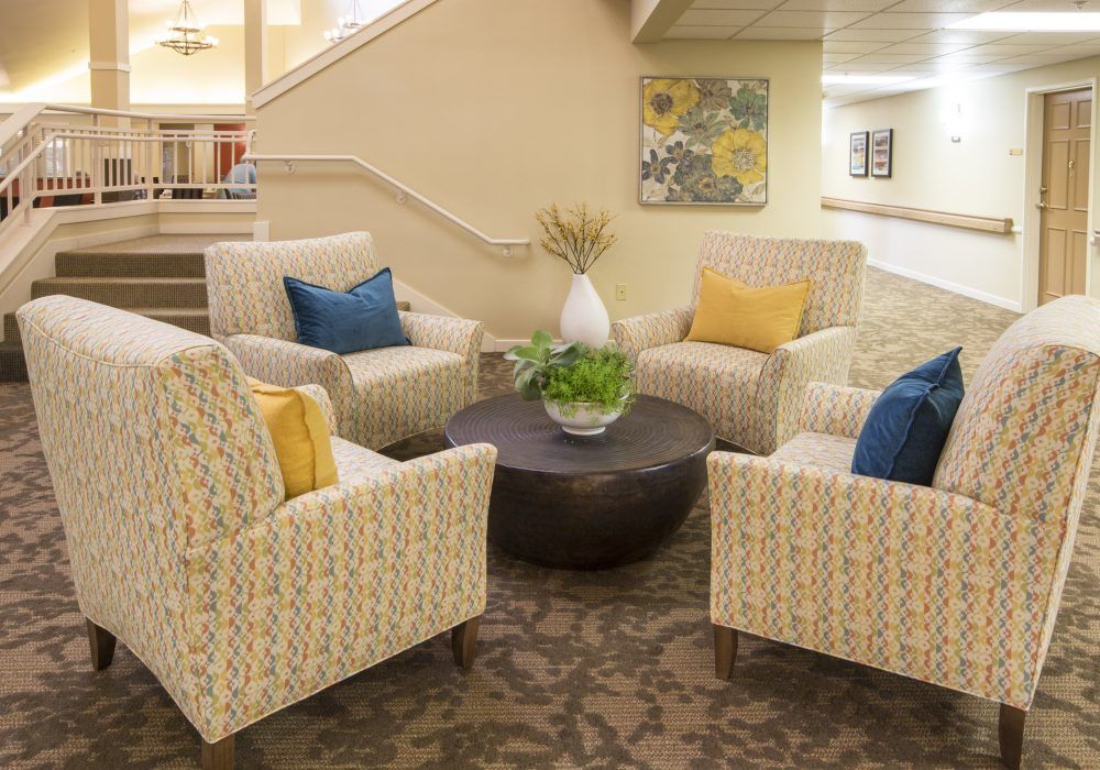 A cozy seating area with patterned armchairs, colorful cushions, and a central table adorned with a plant.