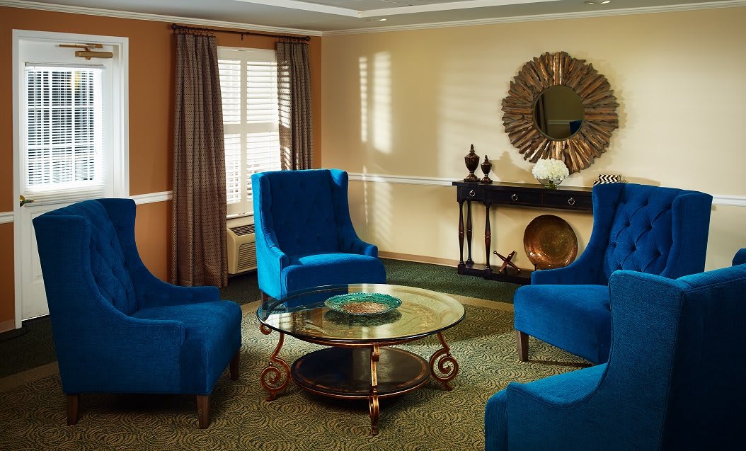 A stylish living room with blue chairs and a glass coffee table.
