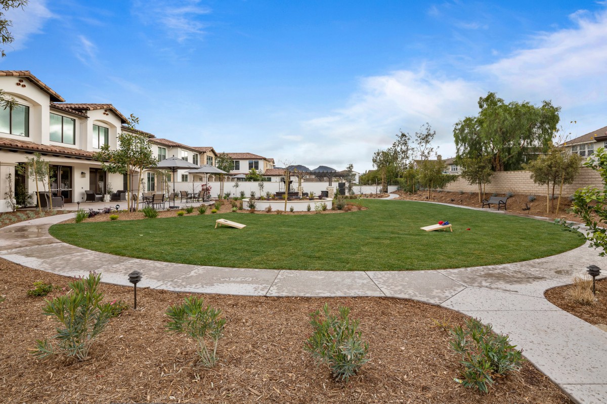 A serene residential neighborhood featuring a well-maintained lawn and a paved pathway under a clear blue sky.