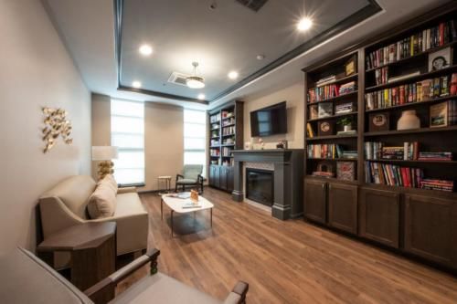 A modern living room with a cozy atmosphere featuring bookshelves, a fireplace, and comfortable seating.