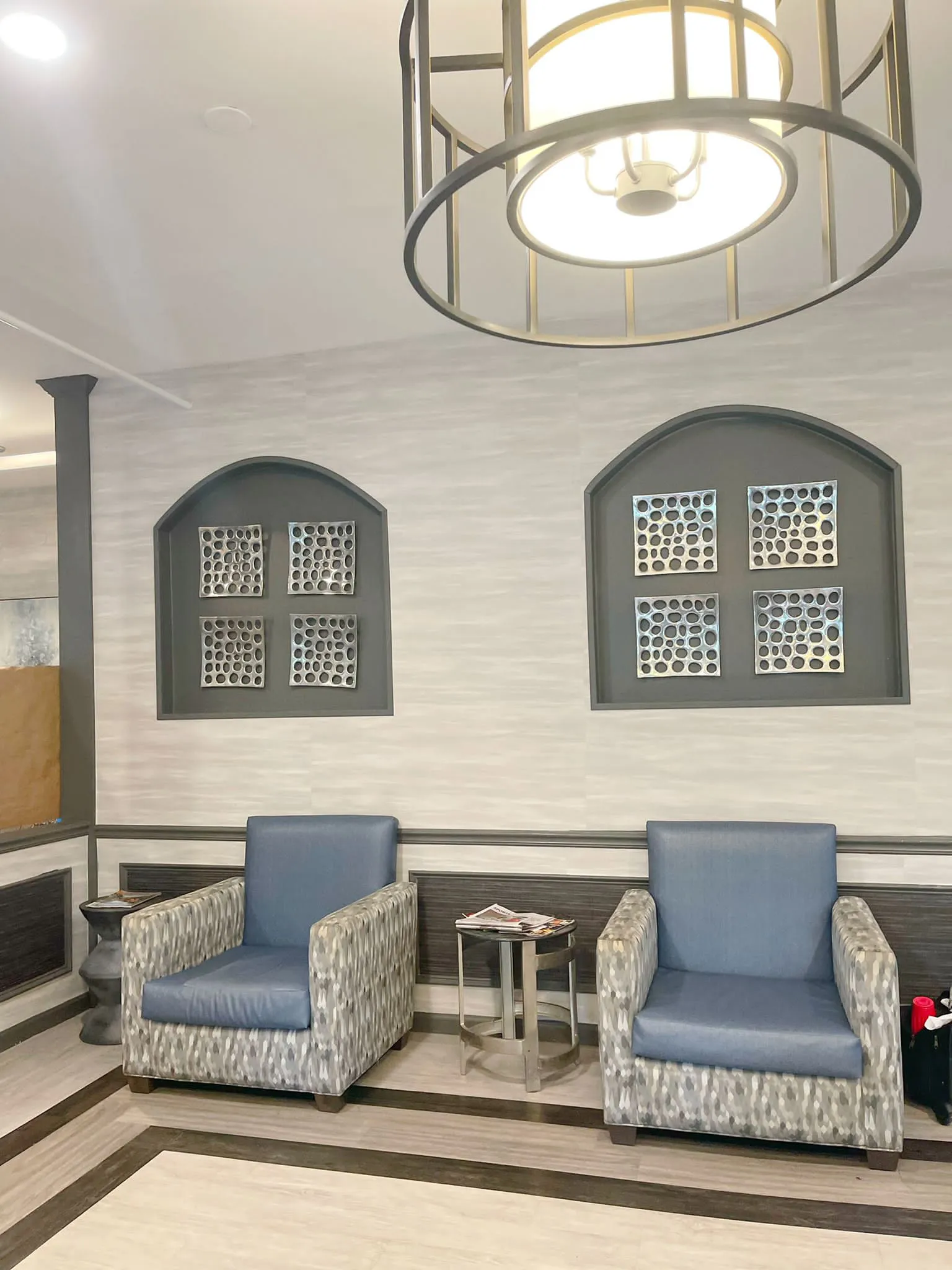 A modern lobby with two upholstered chairs and decorative wall elements.