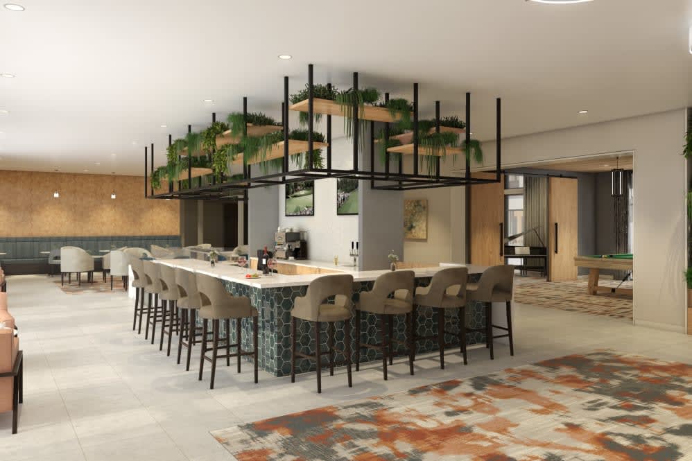 A modern kitchen with a central bar area and stylish seating, featuring overhead greenery.