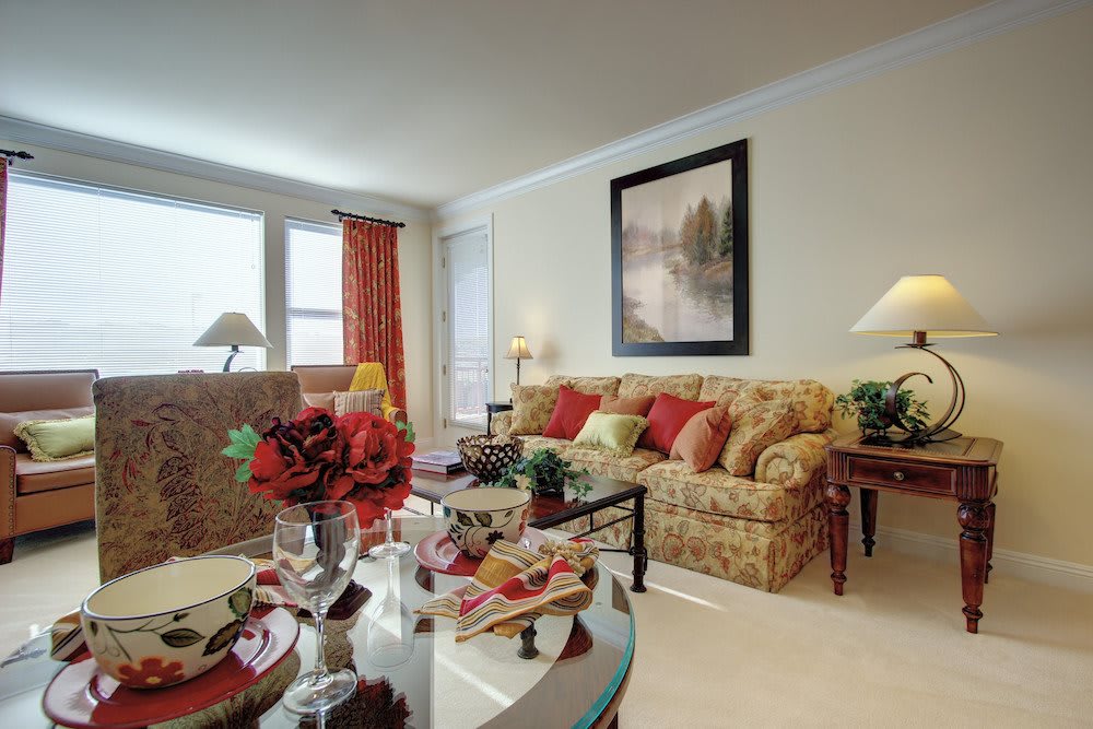 A cozy living room with elegant decor, featuring a sofa, coffee table, and art on the wall.