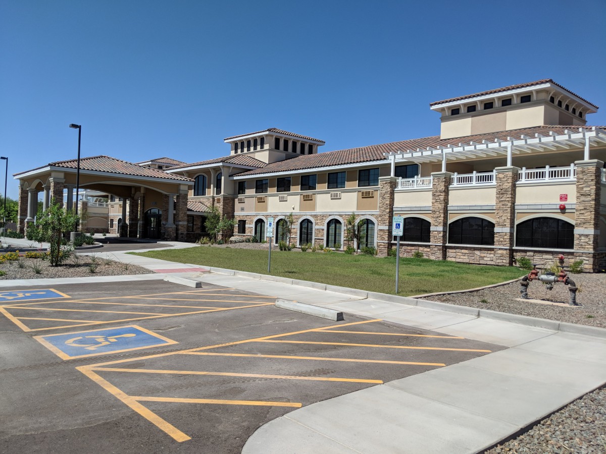 A school building with a large parking lot under a clear blue sky.