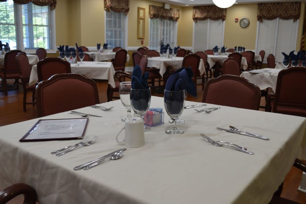 A dining room set with tables and chairs, featuring neatly arranged table settings.