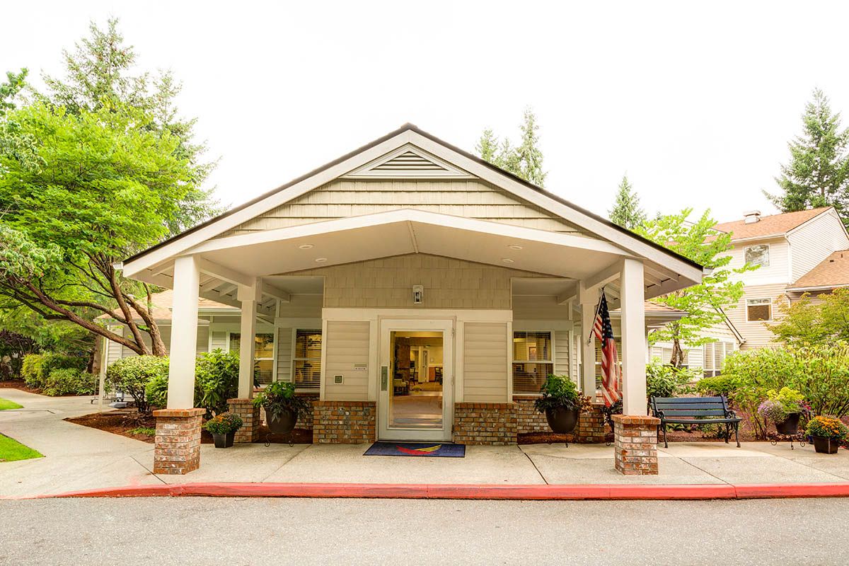 A welcoming building entrance with a covered porch surrounded by greenery.