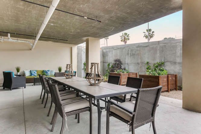 A modern outdoor dining area with a long table, chairs, and decorative lanterns on a patio.
