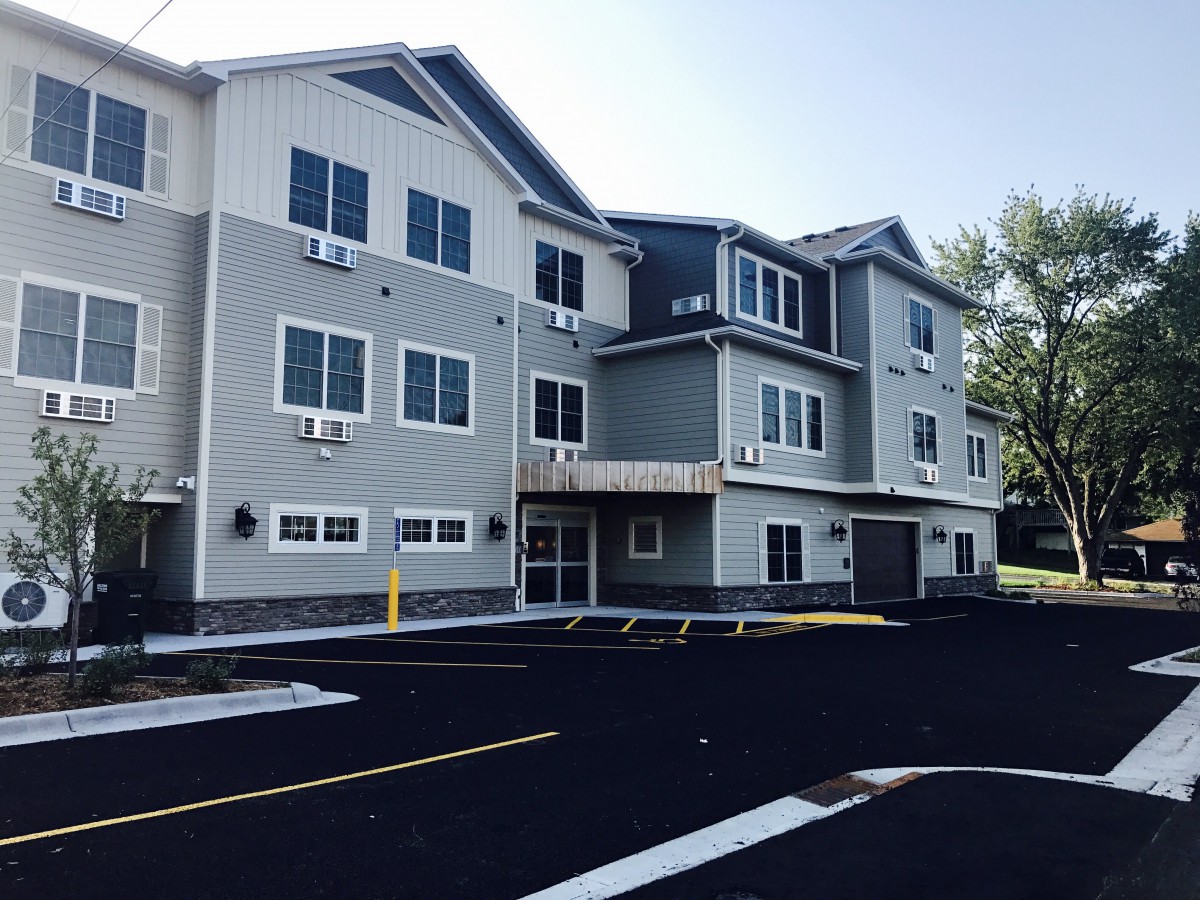 A modern residential apartment building with a parking lot in front.