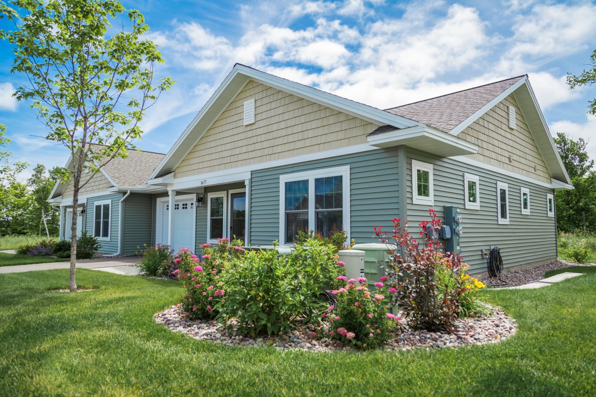 A charming suburban house with well-maintained landscaping under a blue sky.