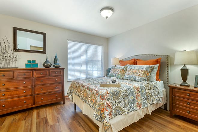 A cozy bedroom with colorful bedding and wooden furniture.