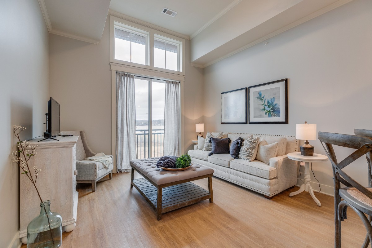 A modern living room with large windows, featuring a cozy sofa and coffee table in a neutral color palette.
